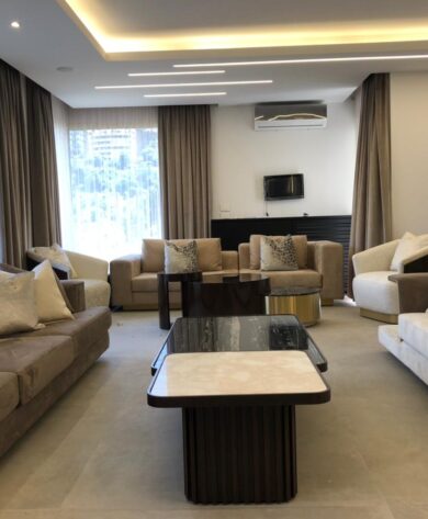 Panoramic view of the elegant living room with two grey and one whit couch, and a marbled table in the center