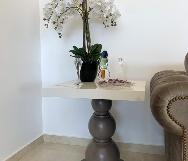 An exquisite looking side table with a marble top and eyecatching accessorus