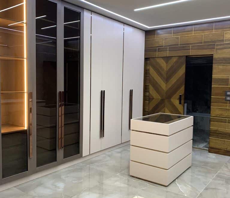 The master bedroom's coff-white closet with its bronze handles and 3 glass panels. (one of the panels is slighly openned to showcase the light feature. In the background you can see the hiddden door for the bathroom